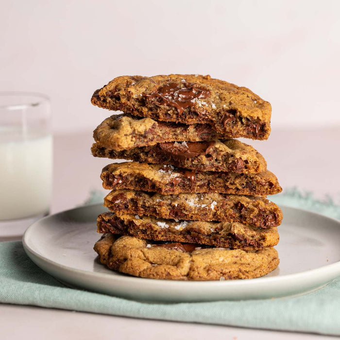 Stack of chocolate chip cookies with a glass of milk in the background