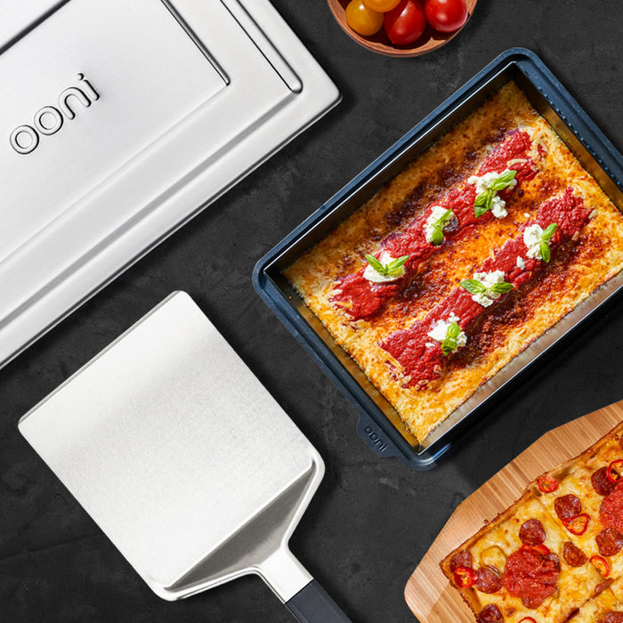 Ooni Pan Pizza Spatula next to Ooni Detroit-Style pizza pans | Click this image to open up the product gallery modal. The product gallery modal allows the images to be zoomed in on.