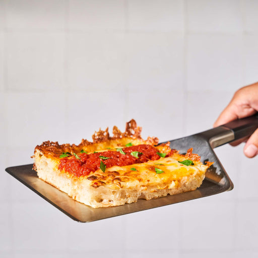 Ooni Pan Pizza Spatula holding Detroit-style pizza slice