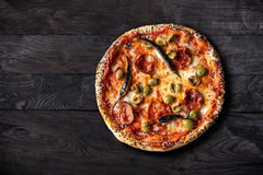 Pizza topped with salami, green chilli and olives