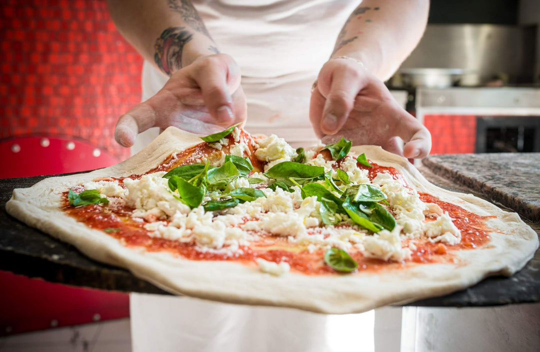 hands preparing a margherita pizza