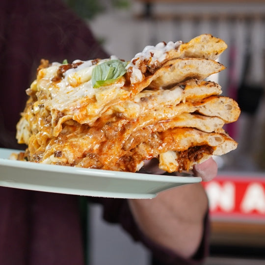 Pizzas stacked on top of each other with a beschamel sauce and ragu between layers