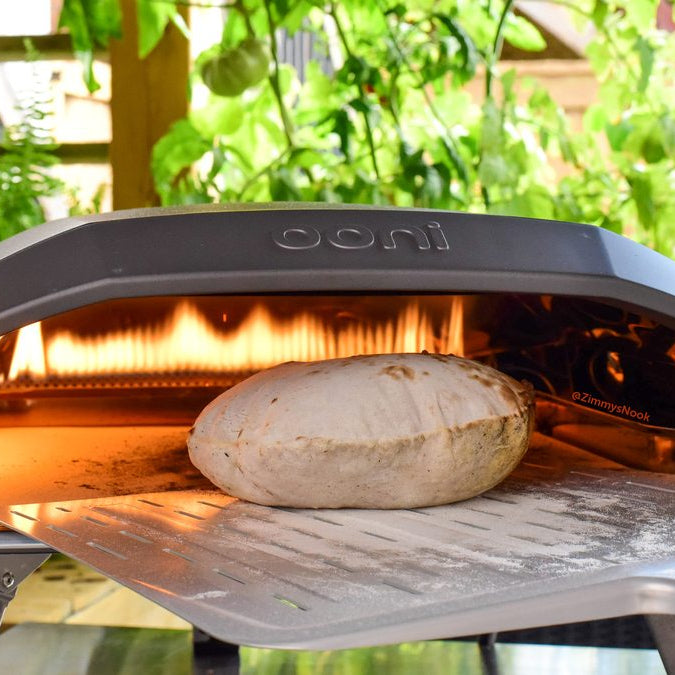 Moroccan flatbread being inserted into a pizza oven with a pizza peel. Made using a Moroccan flatbread recipe.