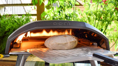 Moroccan flatbread being inserted into a pizza oven with a pizza peel. Made using a Moroccan flatbread recipe.