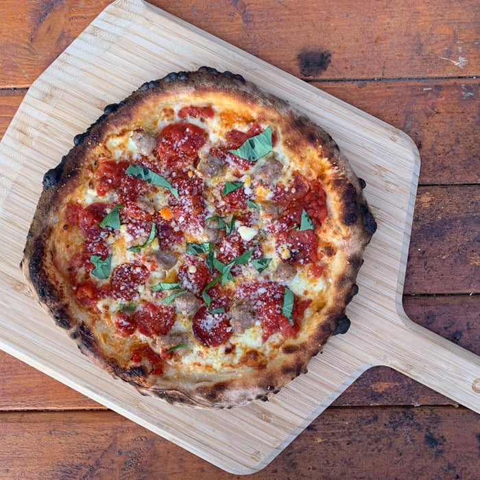 Thin Crust Pizza on a wooden pizza peel baked using a Thin Crust Pizza Dough recipe