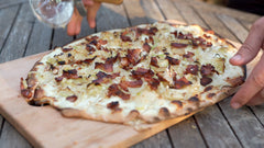 Traditional Flammkuchen on a wooden chopping board cooked using a Flammkuchen recipe