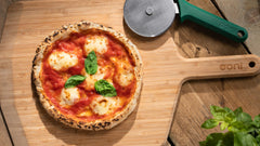 Pizza topped with cheese, tomatoes and basil on a wooden pizza peel, made using a Gluten-Free Pizza Dough recipe