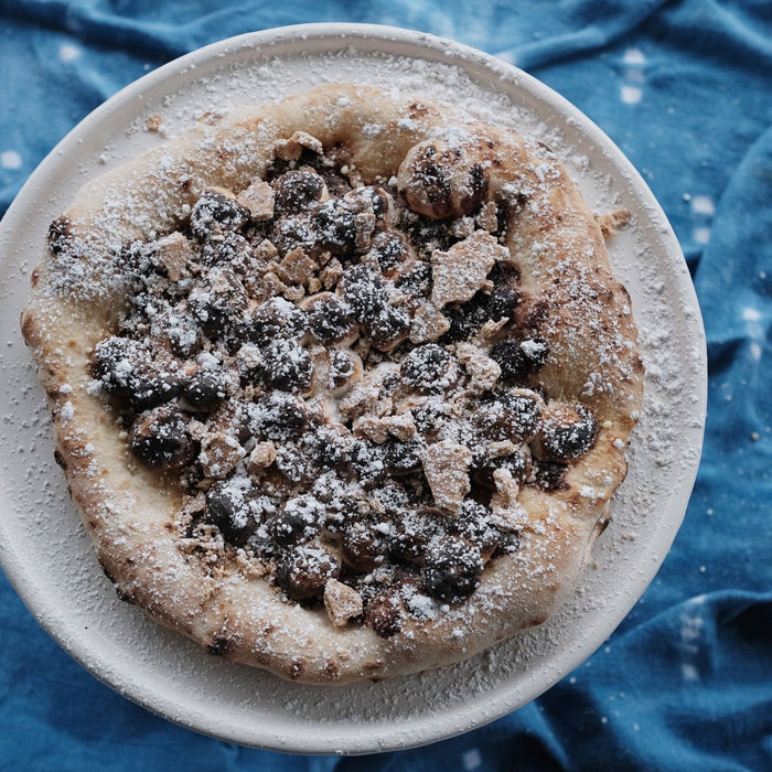A pizza topped with chocolate, marshmallows and crushed Graham crackers made using a S’mores pizza recipe