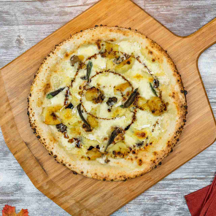 Crispy Roast Potato and Truffle Pizza with Brie and Sage on a bamboo pizza peel