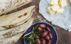 Bread, olives and butter on a wooden table top