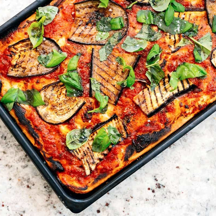 Sicilian pizza topped with cheese, tomato and eggplant baked in a steel baking pan, using a Sicilian pizza recipe