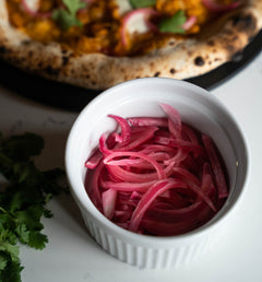 Pickled red onions in a white ramekin