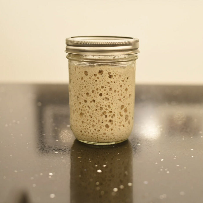 Sourdough starter in a jar on a marble table.