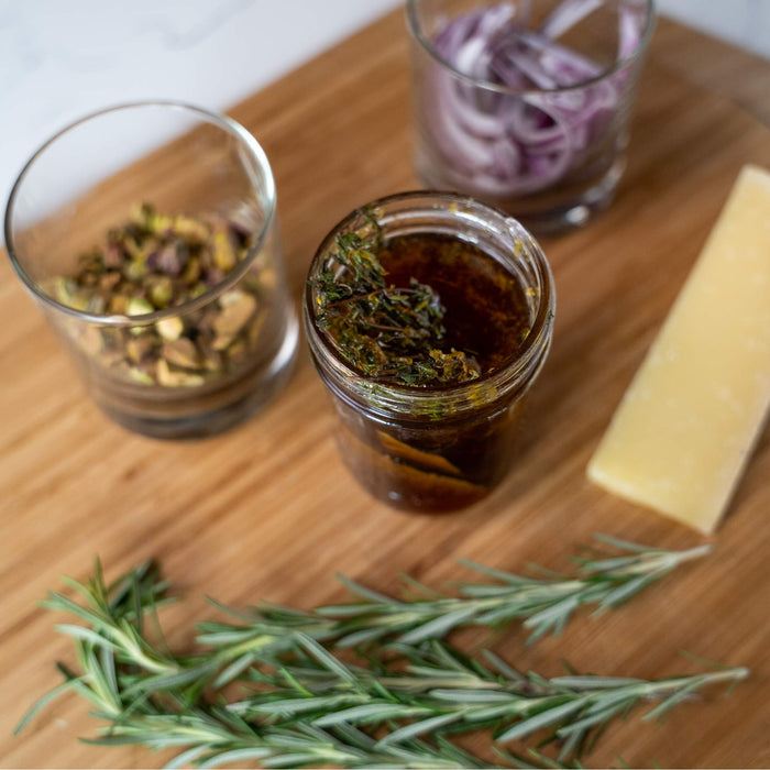 Thyme, Meyer Lemon and Bay Leaf-Infused Honey in glass jars on a wooden pizza peel with fresh thyme