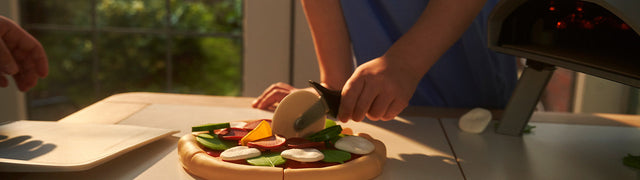 Child playing with pizza toy slicer cutting toy pizza
