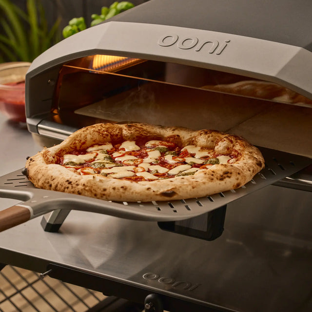 Ooni pizza oven with a freshly baked pizza on a aluminum signature pizza peel.