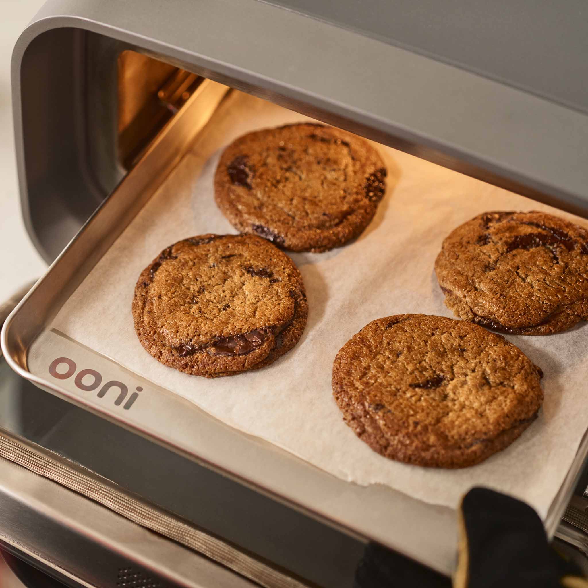 Baked chocolate chip cookies on sheet pan in Ooni Volt 2 electric pizza oven.