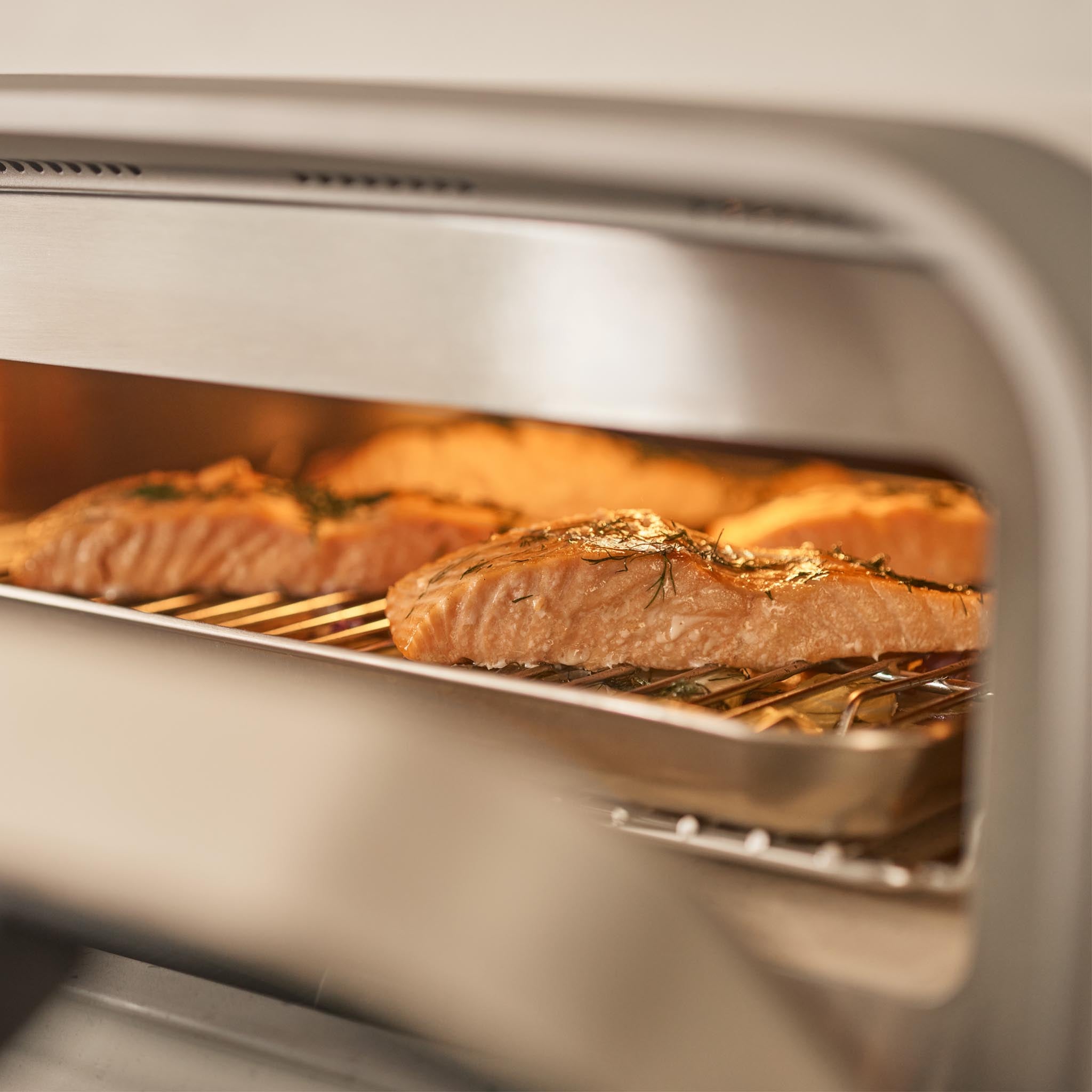 Salmon filets cooking inside Ooni Volt 2 Electric Pizza oven on an Ooni Sheet Pan and Rack. 
