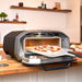 Pizza peel launching into Ooni Volt 12 Electric Pizza Oven