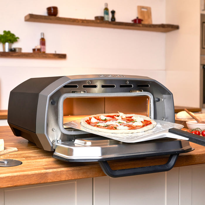 Pizza peel launching into Ooni Volt 12 Electric Pizza Oven | Click this image to open up the product gallery modal. The product gallery modal allows the images to be zoomed in on.